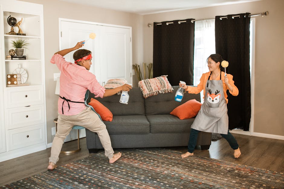 A joyful couple engages in a playful cleaning fight in their living room, showcasing light-hearted domestic life.